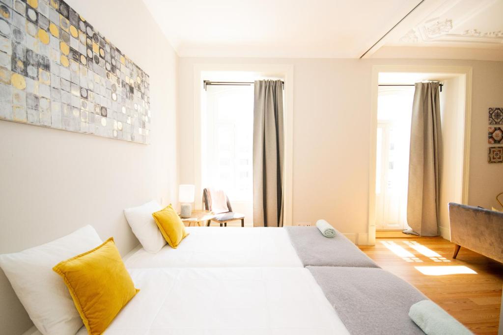 Bright bedroom with twin beds, yellow pillows, gray curtains, and abstract wall art.