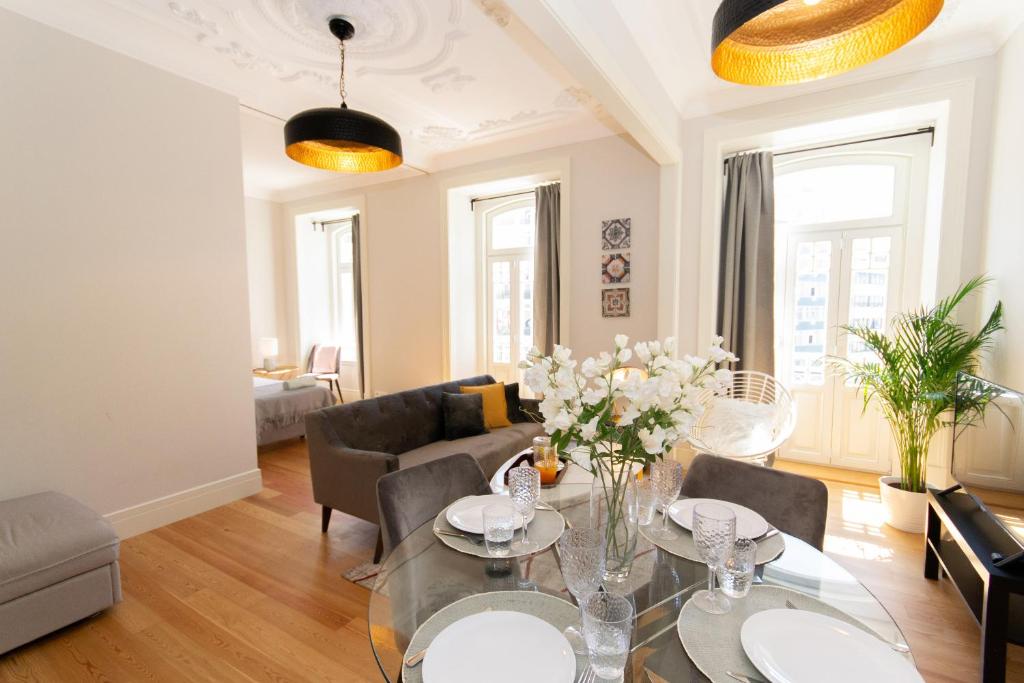 Bright dining and living area with a round glass table set for four and a large gray sofa.