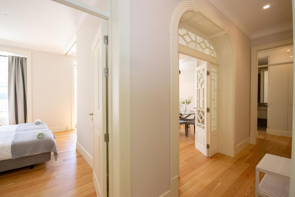 Bright hallway with wood flooring, open doors, and a glimpse of a bedroom and dining area.