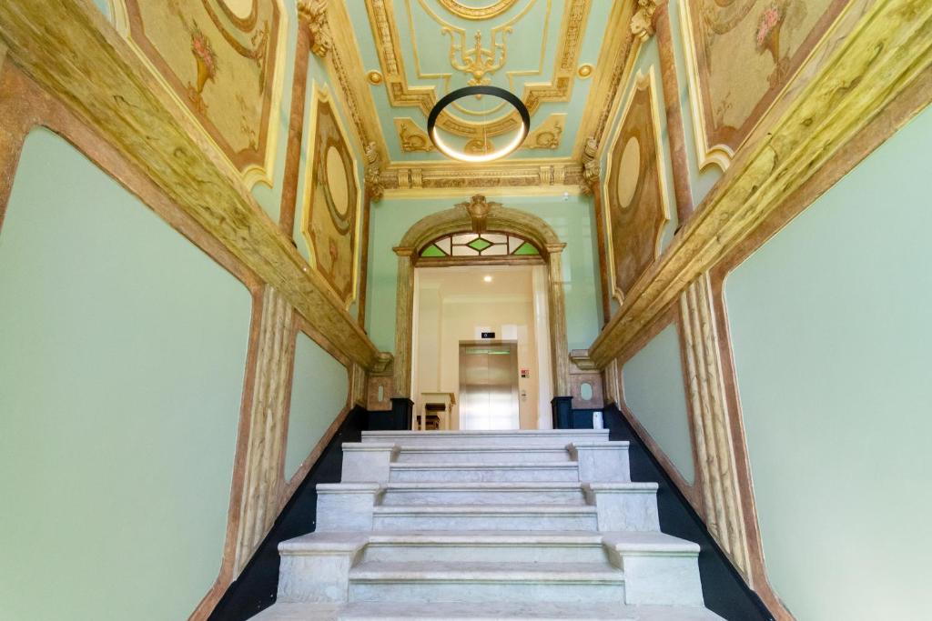 Indoor staircase leading to an elevator with ornate painted walls and a decorative blue ceiling.
