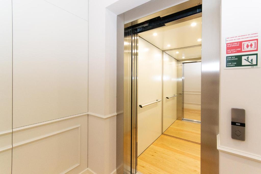 Open elevator with wood-like floor and white walls inside a light-colored hallway.