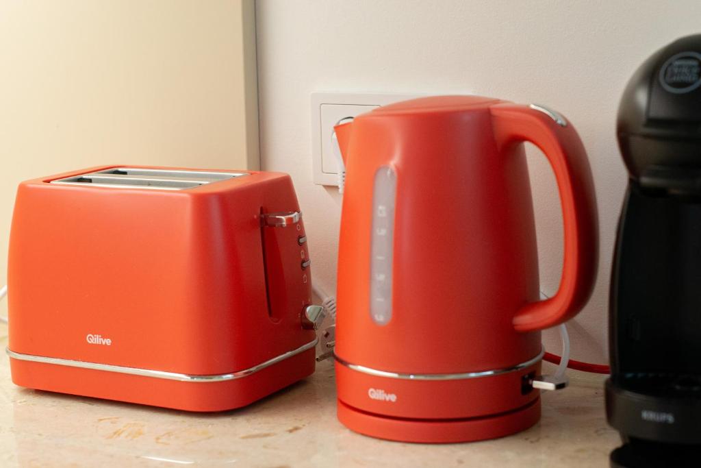 Red Qilive electric kettle and toaster on a kitchen countertop near a power outlet.