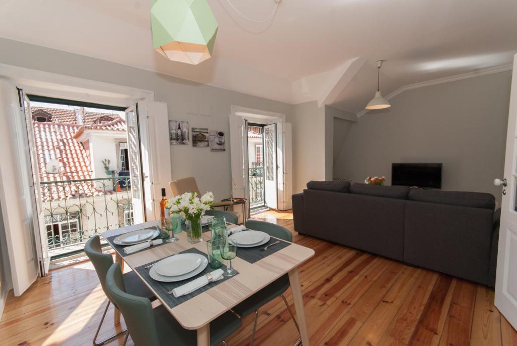 Bright living room with wooden floors, dining table set for four, and open doors leading outside.