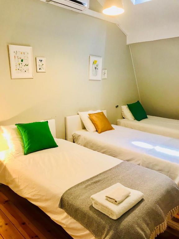 Three single beds with white linens and colorful pillows in a neatly arranged bedroom.