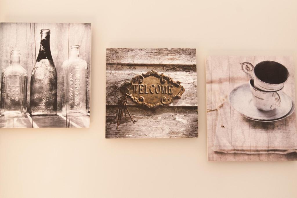 Three sepia-toned square wall art pieces: vintage bottles, a welcome sign with keys, and a coffee cup on a saucer.