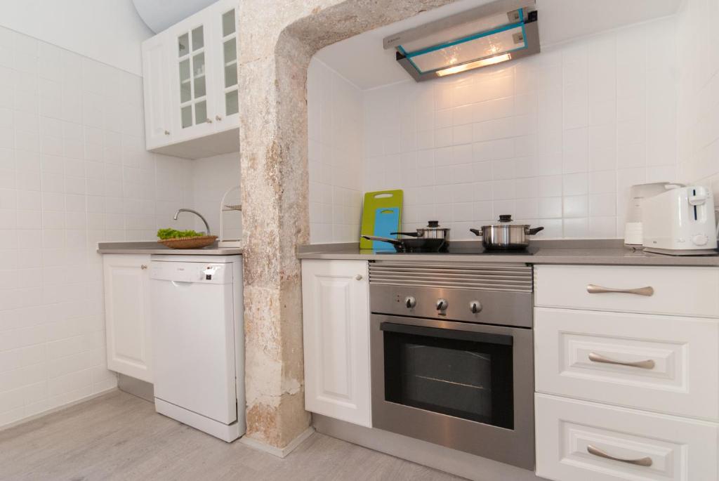 Modern kitchen with white cabinets, dishwasher, stainless steel oven, stove, and stone arch detail.