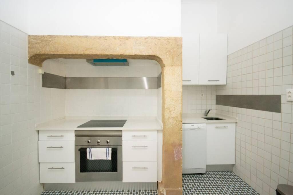 Compact kitchen with white cabinets, electric stove, oven, small sink, and patterned tile floor.