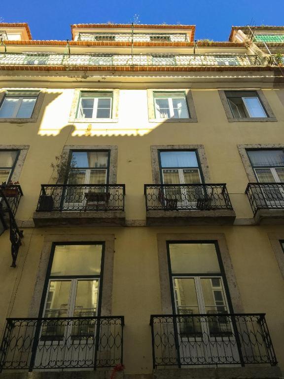 Facade of a yellow building with black wrought iron balconies under a clear blue sky.