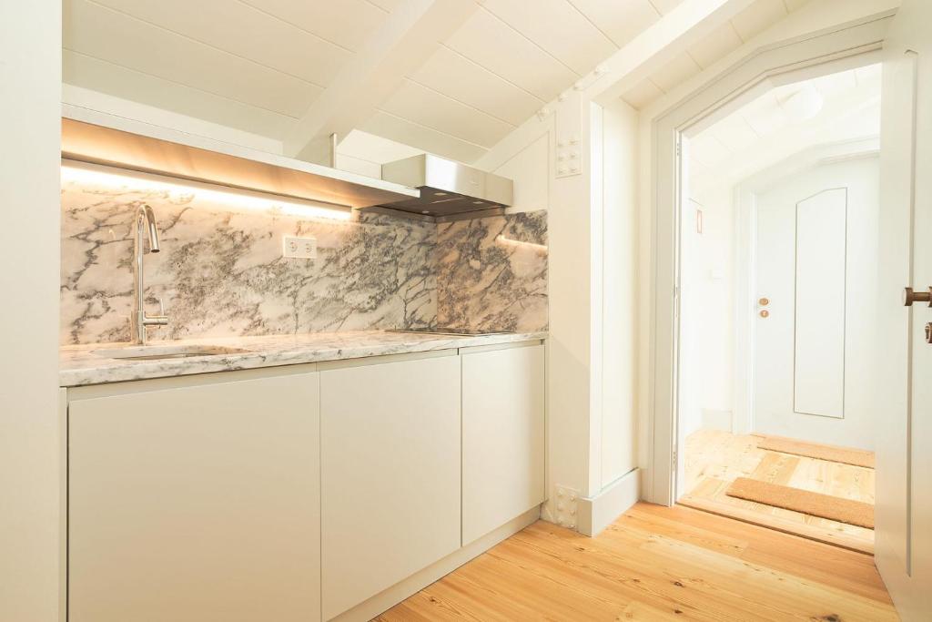 Compact modern kitchen with marble countertop, backsplash, stainless steel faucet, and wooden floor.
