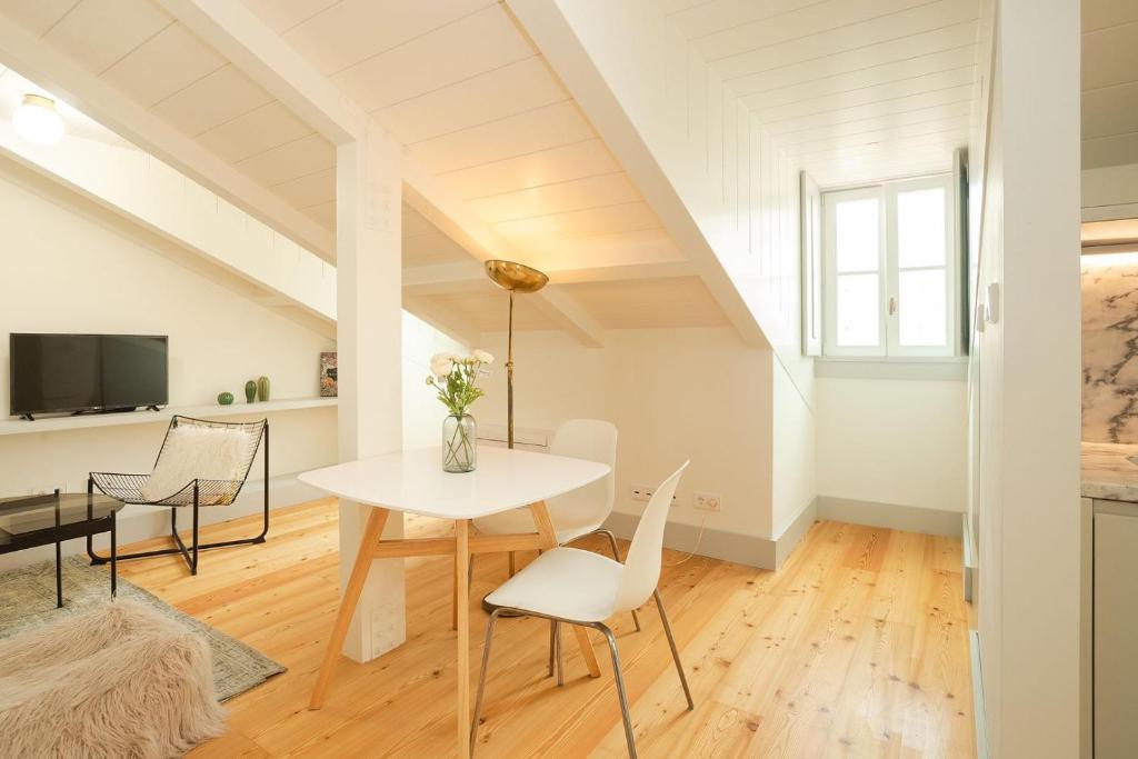 Bright attic dining area with white table, chairs, a floor lamp, and a small TV on a low shelf.
