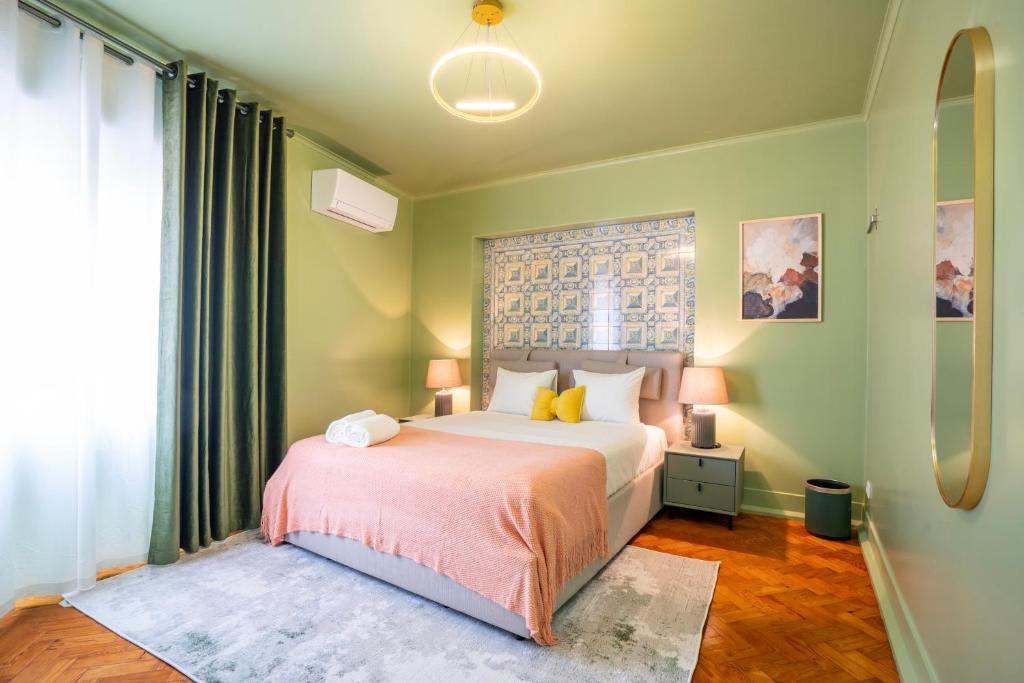 Cozy bedroom with green walls, queen bed with pink throw, bedside lamps, and patterned headboard.