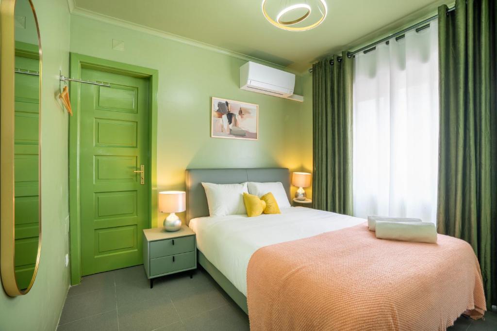 Cozy bedroom with green walls, bed with white bedding, yellow pillows, peach blanket, nightstands, and curtains.