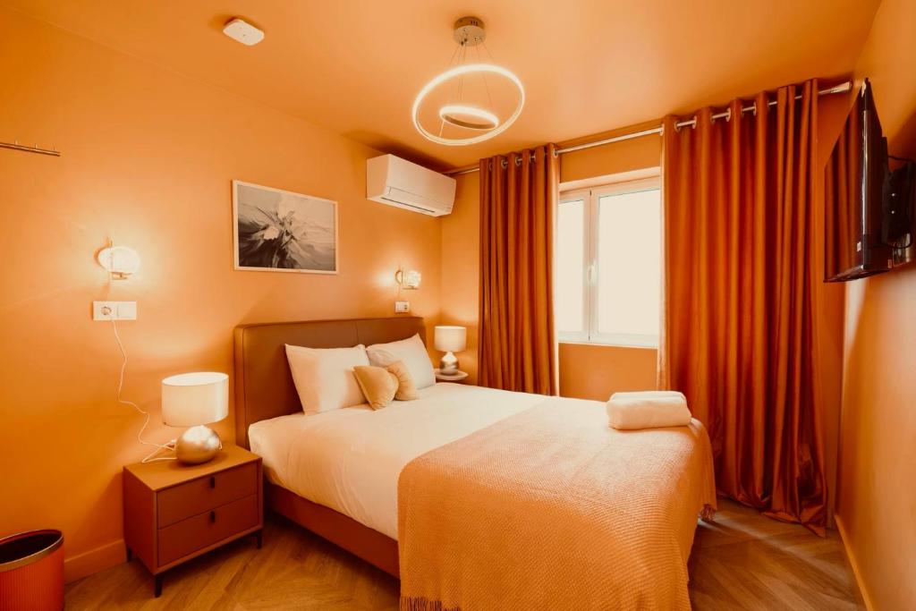 Orange-themed bedroom with a bed, bedside tables, curtains, and modern circular ceiling light.