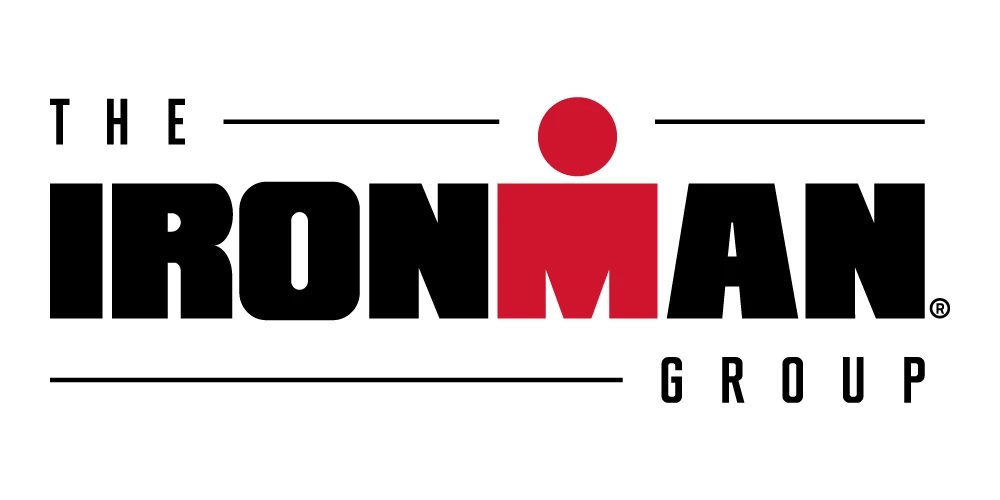 Logo of The Ironman Group with the word IRONMAN in bold black letters and the letter M stylized in red with a red dot above it, and the words THE and GROUP in smaller black text.
