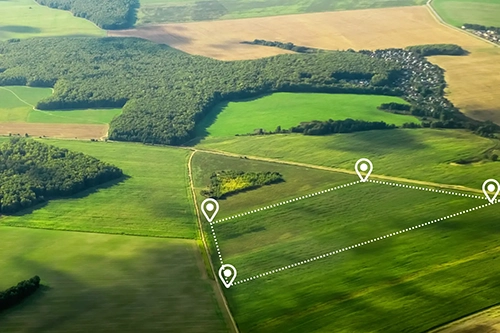 Aerial view of green and brown farmland with white digital markers outlining a rectangular plot.