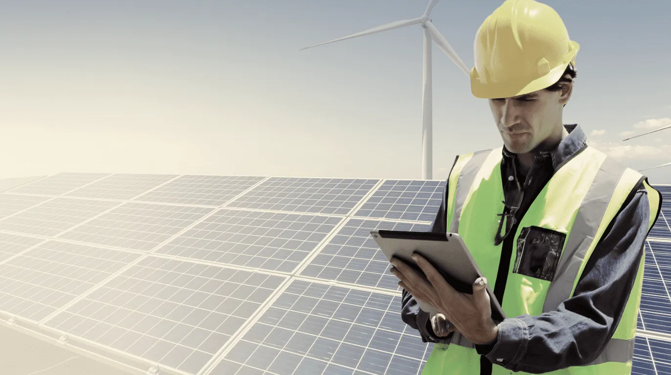 A technician next to some solar panels looking at a tablet