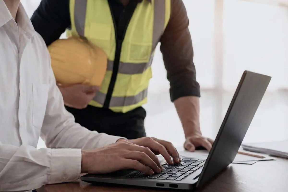 A planner working at computer on SAP with a technician next to them