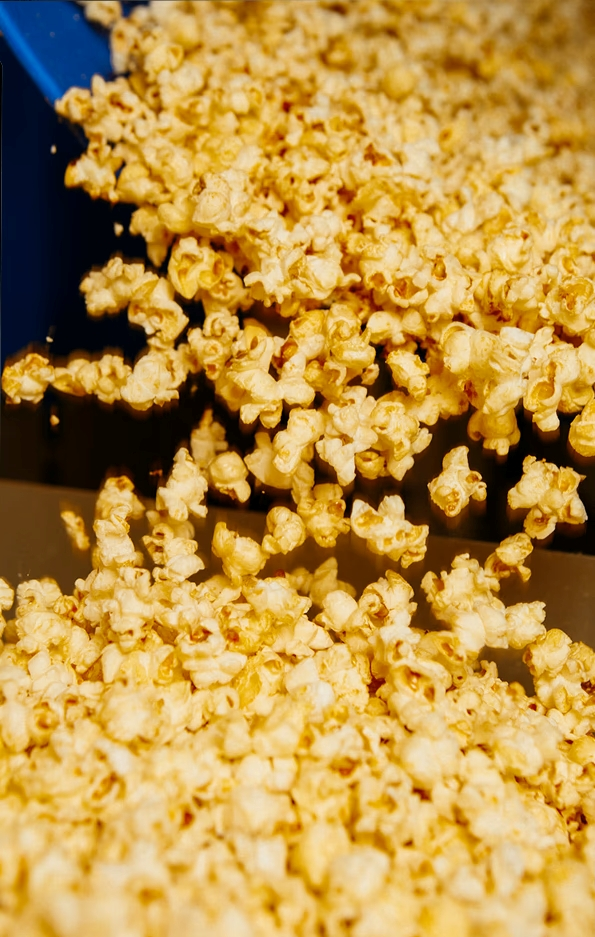 Close-up of freshly popped popcorn being poured from a blue container.