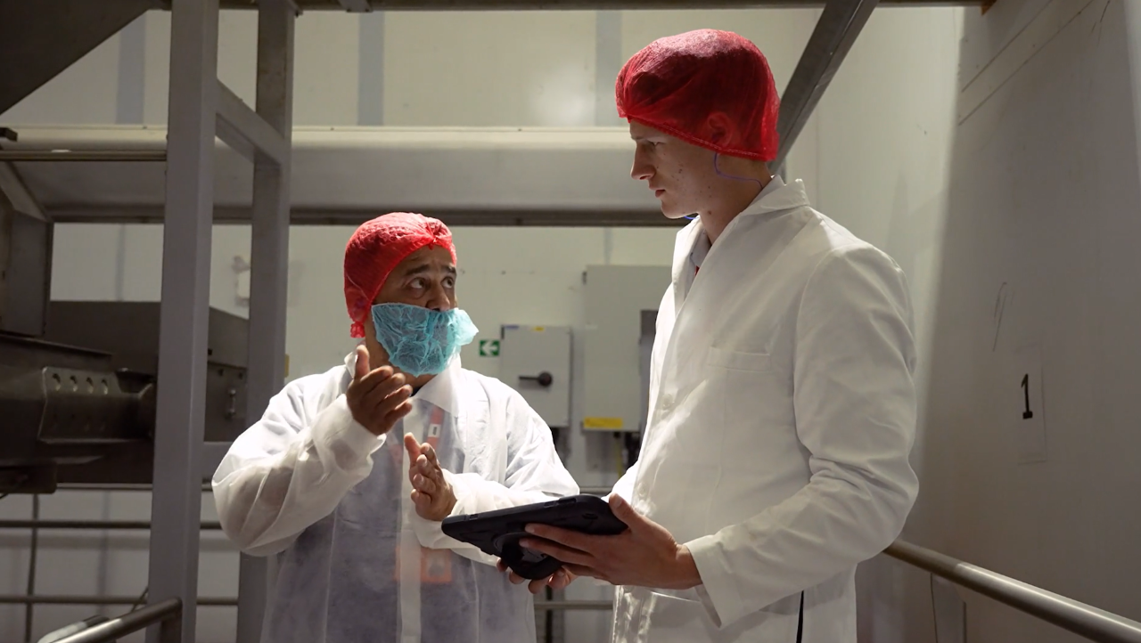 Six men standing indoors posing for a group photo, dressed in various formal and semi-formal outfits.