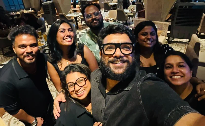 Beyond Team posing closely for a selfie in a warmly lit indoor setting.