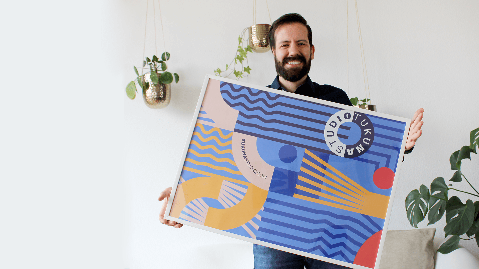 Smiling man holding a framed Tukuna Studio geometric art print