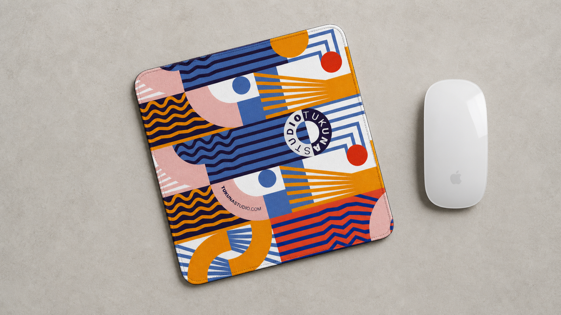 Colorful Tukuna Studio desk mat beside a white computer mouse