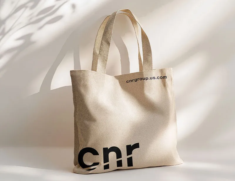 Beige canvas tote bag with 'cnr' printed in large black letters and 'cnrgroup.us.com' in smaller text near the top edge.