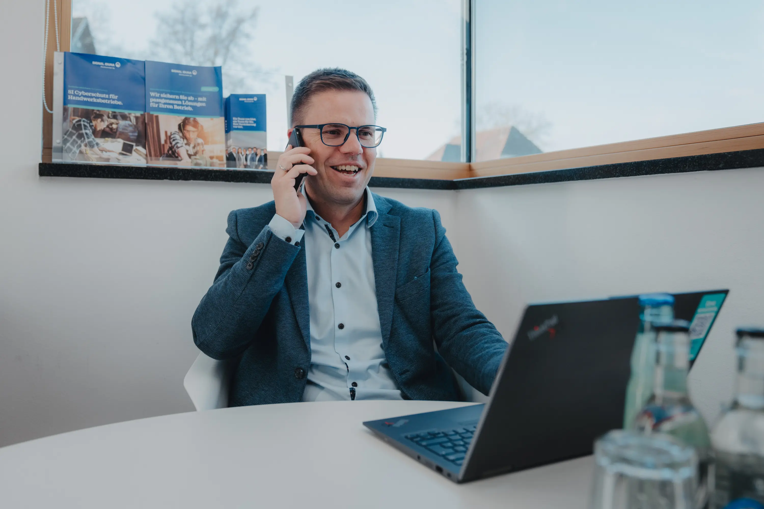 Zwei Männer mit verschränkten Armen stehen vor einer Wand, die mit US-Dollar-Scheinen bedeckt ist.