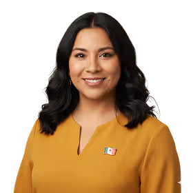 Smiling woman with dark hair wearing a mustard yellow top and a small Mexican flag pin.