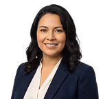 Portrait of a smiling woman with dark hair wearing a white top and dark jacket.