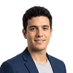 Portrait of a young man with short dark hair wearing a blue blazer over a light gray shirt, smiling slightly against a white background.