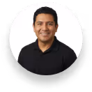 Smiling woman with long black hair wearing a red sleeveless top against a white background.