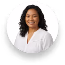 Smiling woman with long black hair wearing a red sleeveless top against a white background.