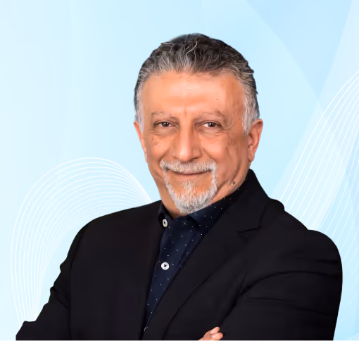 Smiling middle-aged man with gray hair and goatee wearing a dark suit, standing with arms crossed against a blue abstract background.