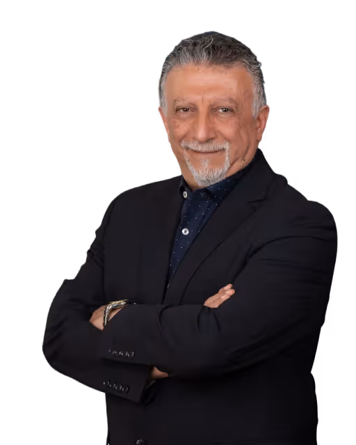 Smiling middle-aged man with gray hair and beard wearing a dark suit jacket and crossing his arms.