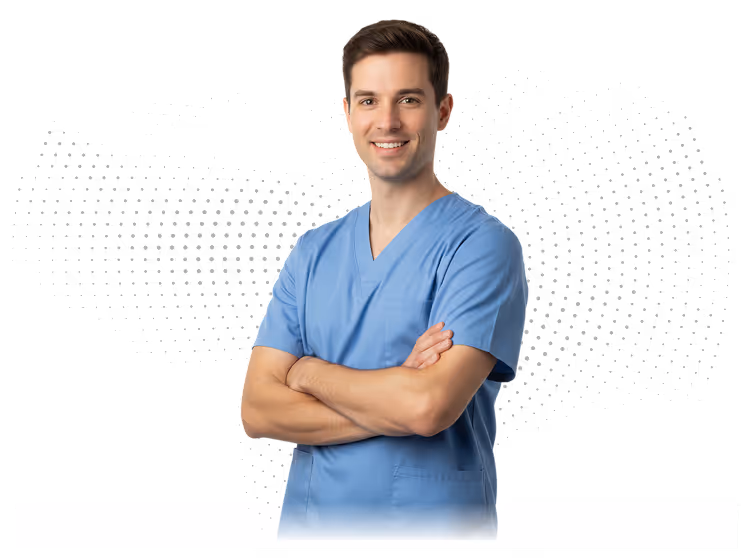 Smiling male healthcare worker in blue scrubs standing with arms crossed against black background.