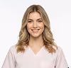 Smiling woman with blonde hair wearing a white shirt against a white background.