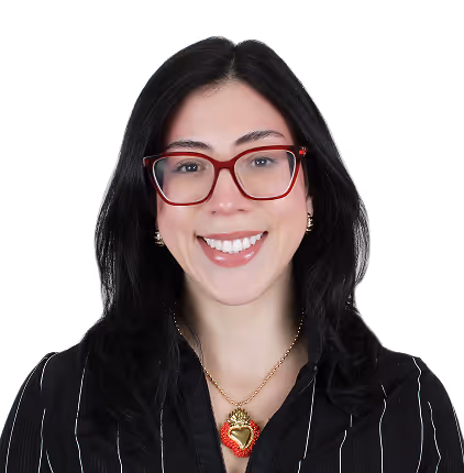 Smiling woman with long dark hair and red glasses wearing a black striped shirt and heart necklace.