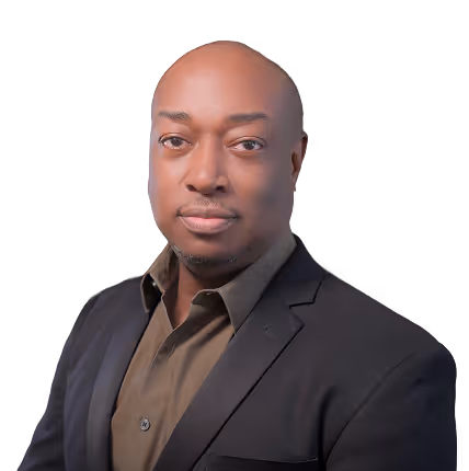 Portrait of a bald man wearing a dark blazer and brown shirt against a transparent background.