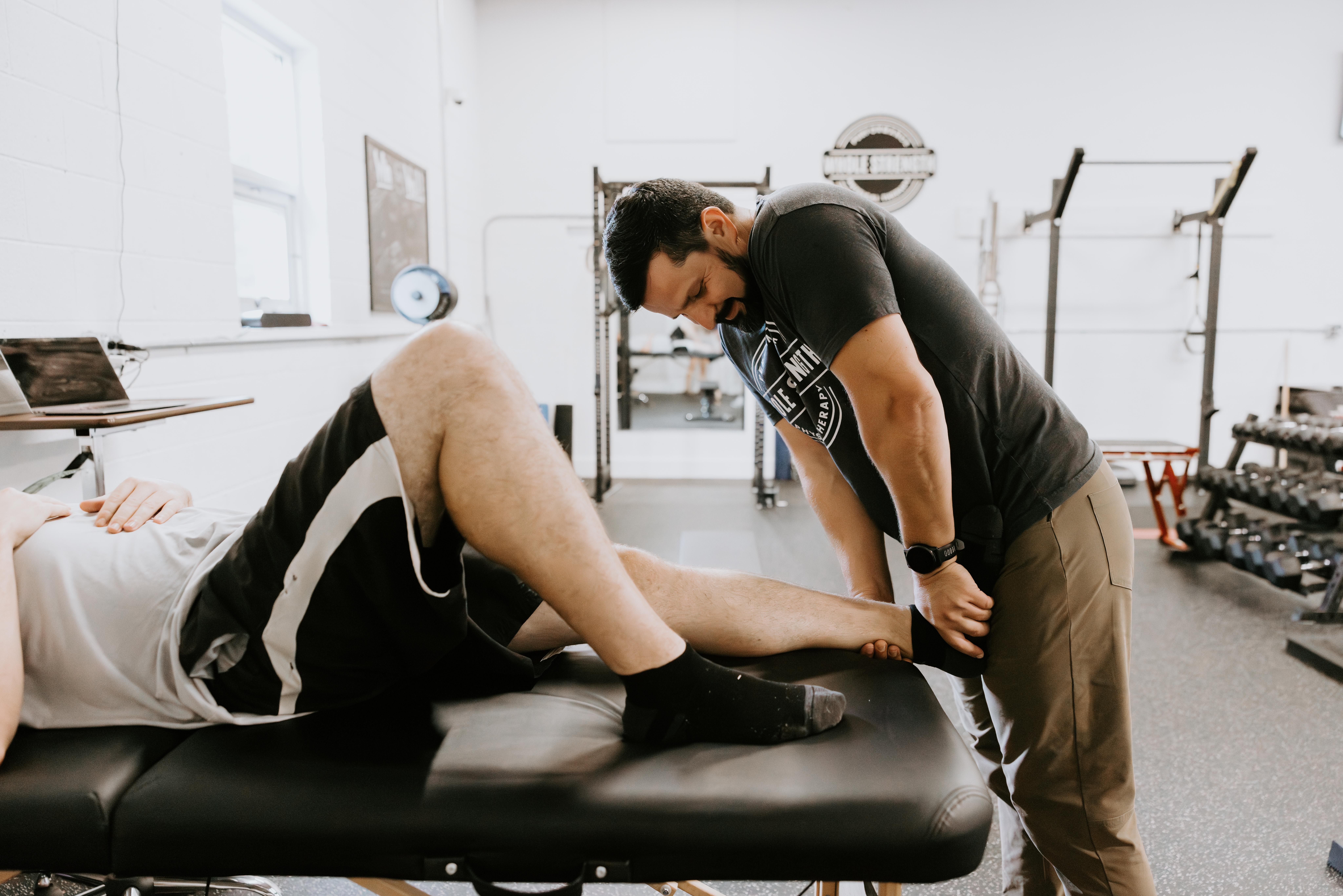 Black and white photo of man facing forward looking down doing a back hold on a machine