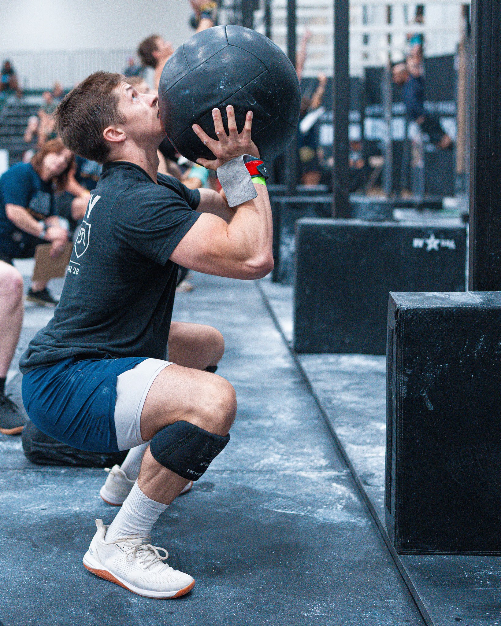 Man in a squat position holding a medicine ball near his chest