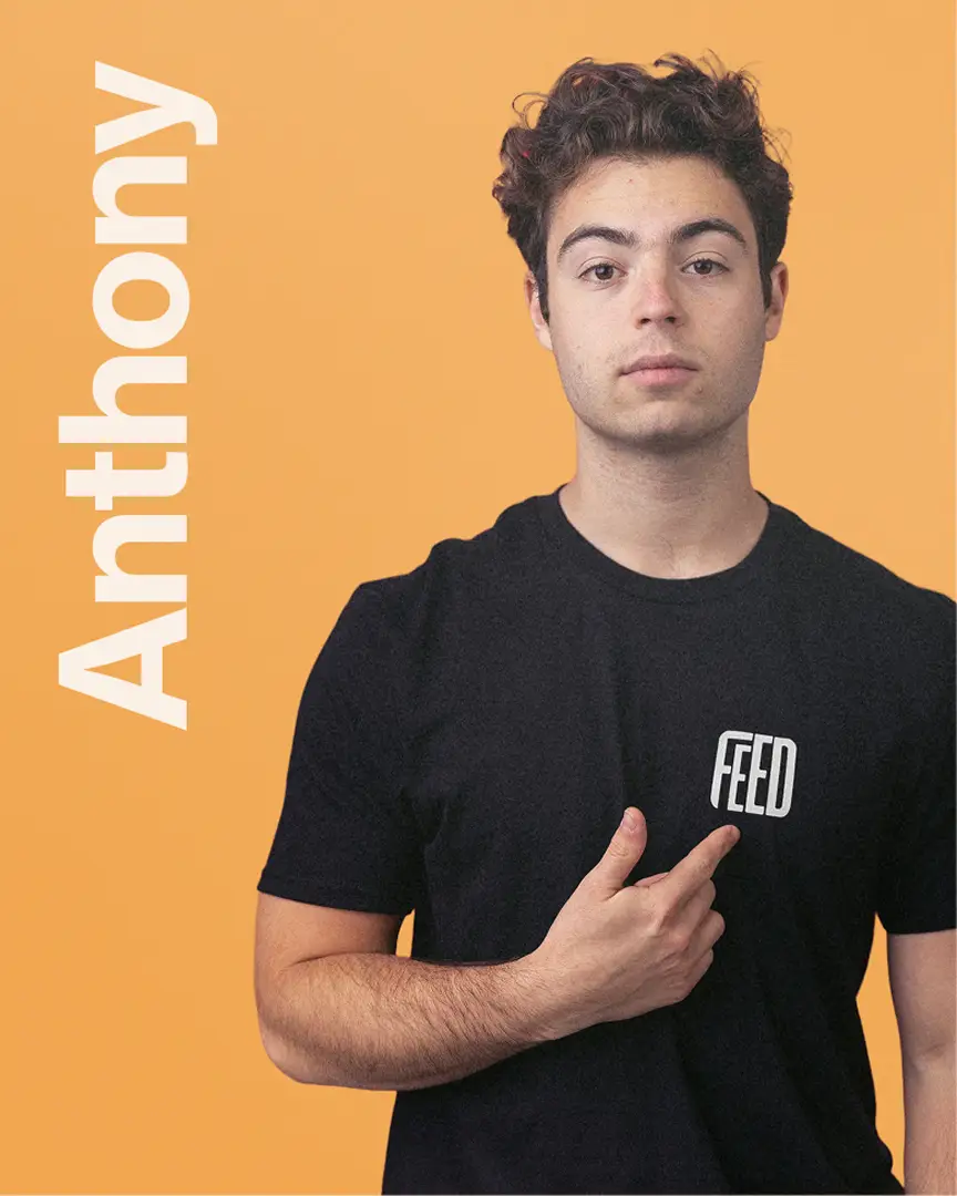 Anthony wearing a black FEED t-shirt, pointing to the logo with the name Anthony displayed vertically.