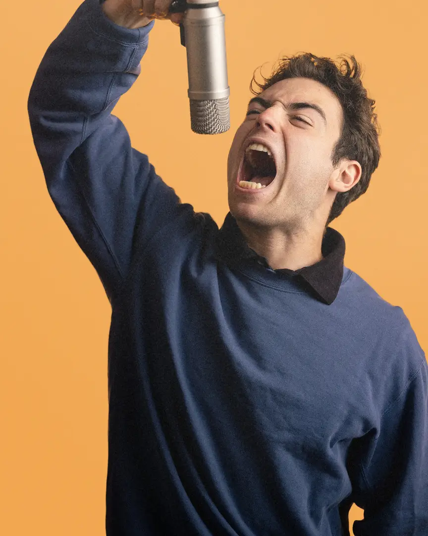 Anthony passionately singing into a silver microphone.