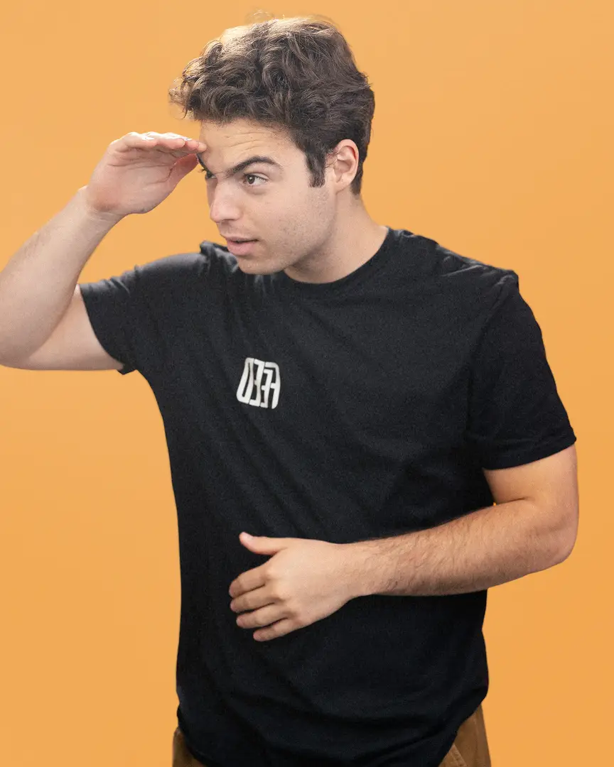 Anthony wearing a black FEED t-shirt looking into the distance with his hand shading his eyes.