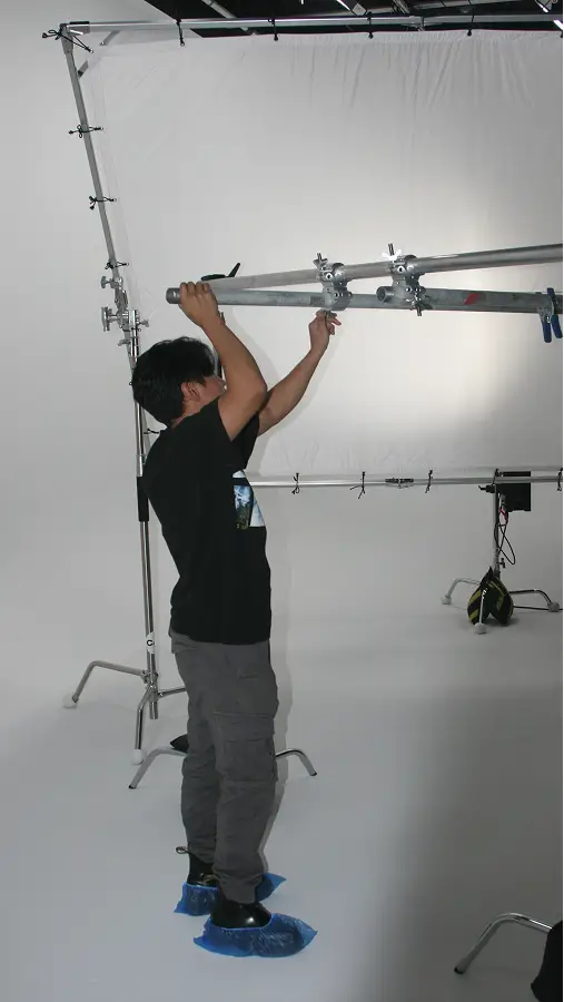 Person adjusting equipment in The CAVE Studio with white backdrop.