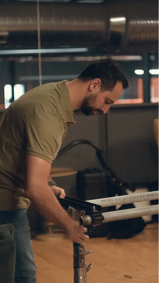 Achi adjusting equipment on a stand in an indoor set setting.