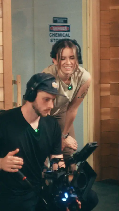 Ben operating a video camera while Emma is reviewing the footage on camera.