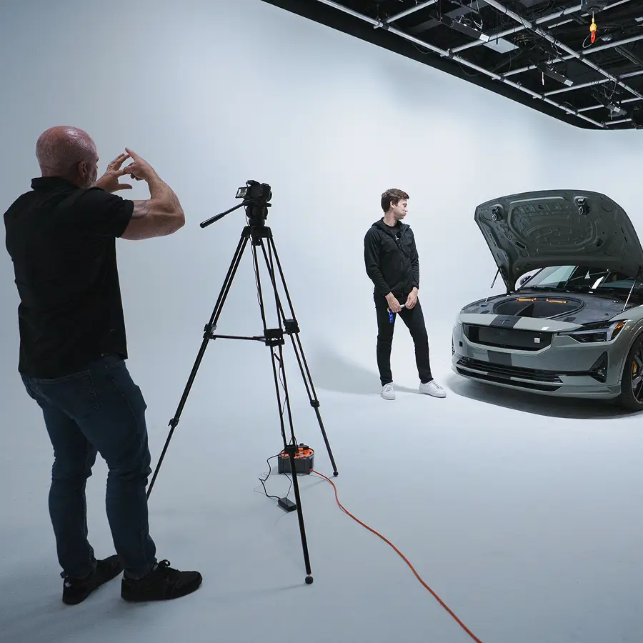 Photographer taking a picture of a man standing next to a car with its hood open in The CAVE Studio.