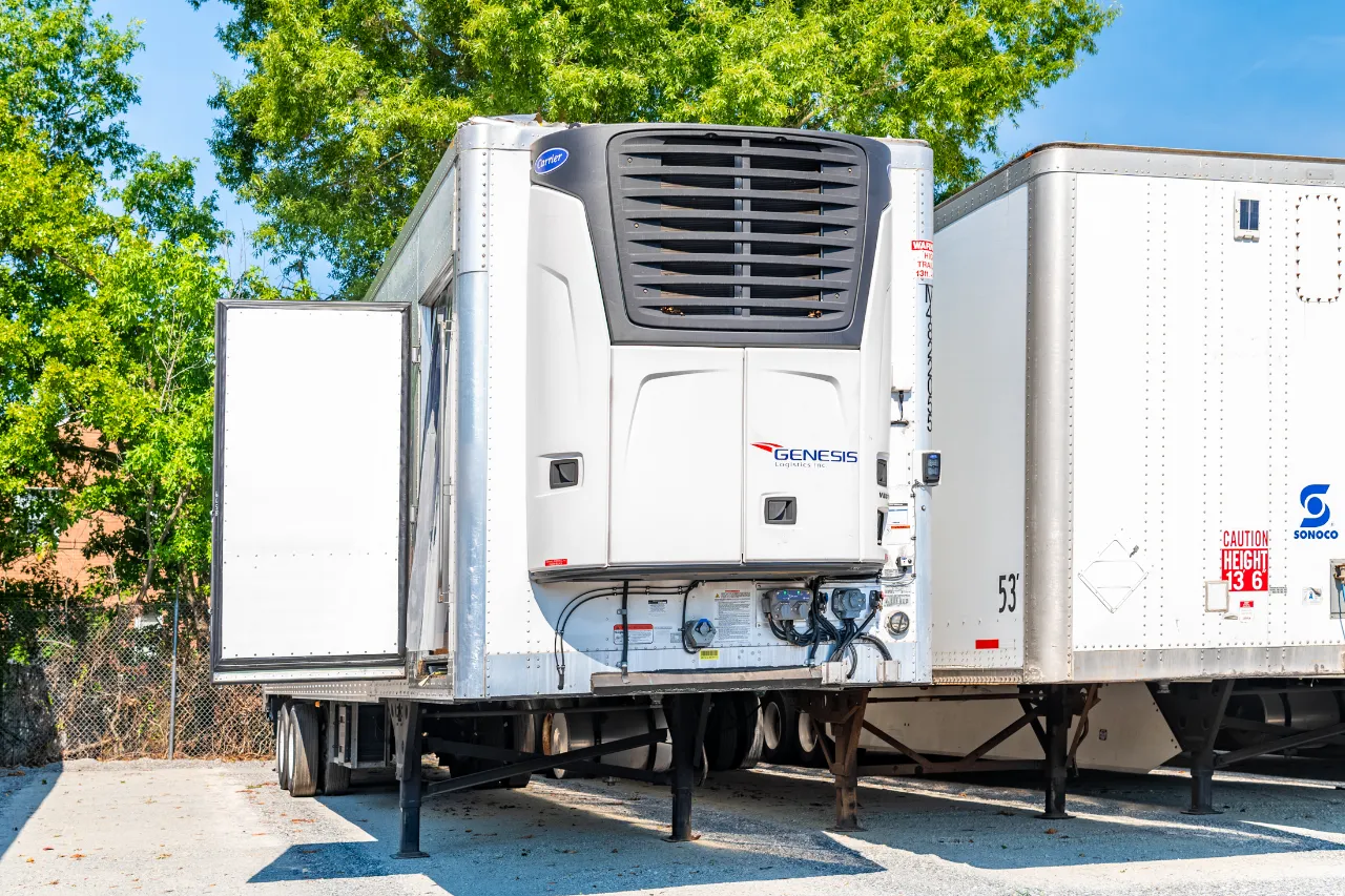 Reefer trailer repair on a refrigerated trailer with a Carrier unit; Genesis Logistics Inc., Sonoco, and Caution Height 13'6" visible.