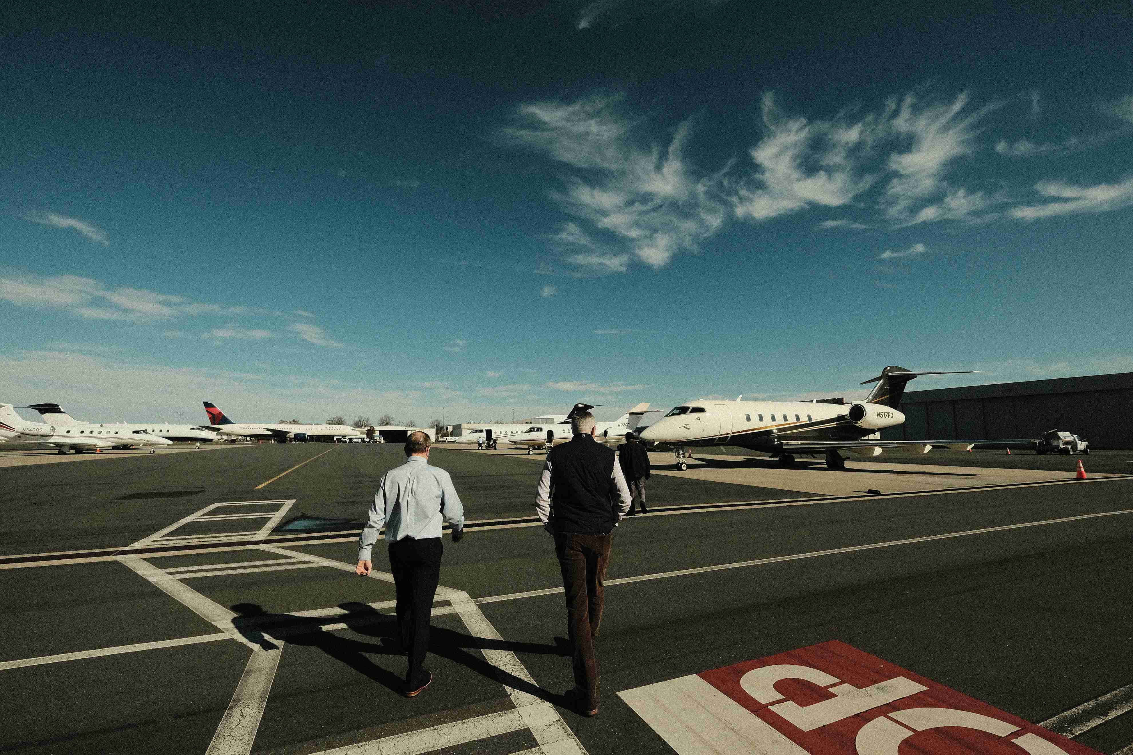 Two business executives walking toward private aircraft on a tarmac